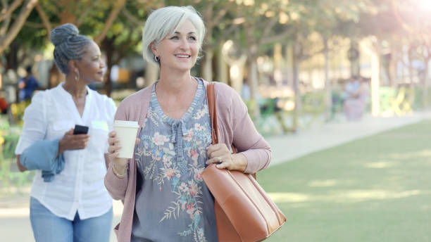 istock Two senior females take a walk through a park together 1070362502