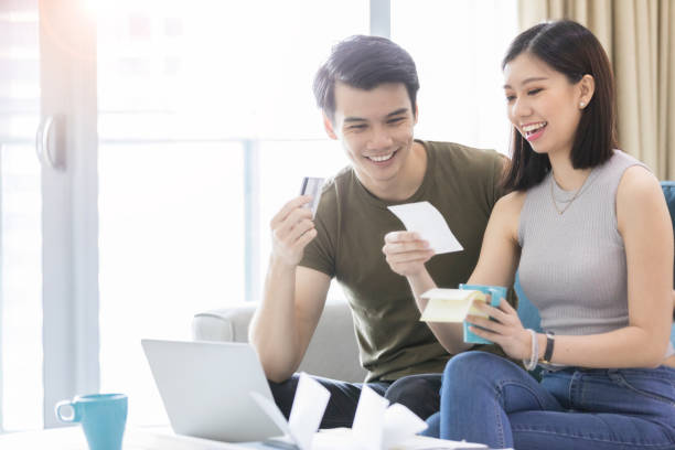 istock A young, married couple sit together and smile at papers, while holding cards 1070362564