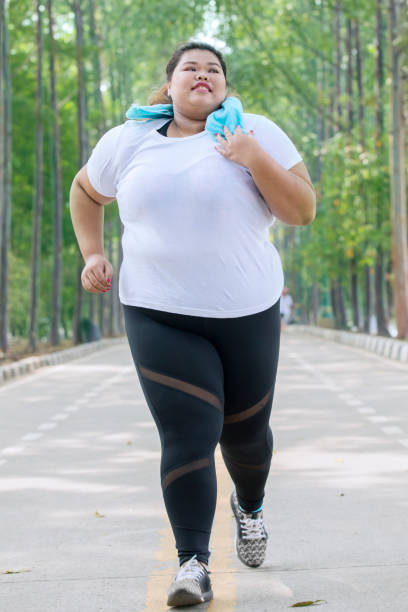 istock Fat female jogger doing a workout on the road 1070377036