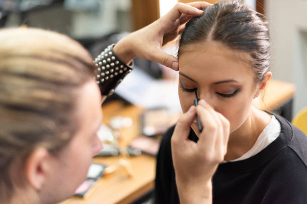 Makeup artist applying eyeliner onto model