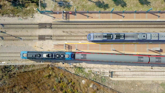 Modern passenger train leaving a train station - Top down aerial view