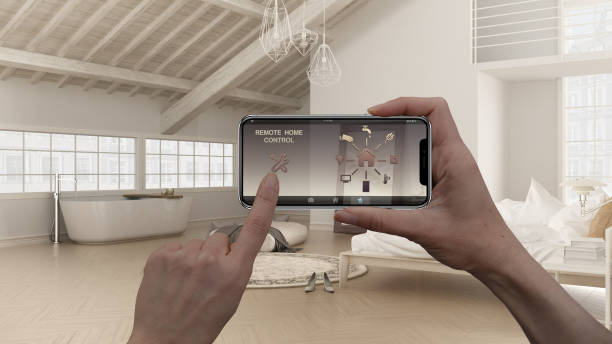 istock Remote home control system on a digital smart phone tablet. Device with app icons. Interior design of loft open space with bedroom and bathroom with bathtub in the background 1070392182