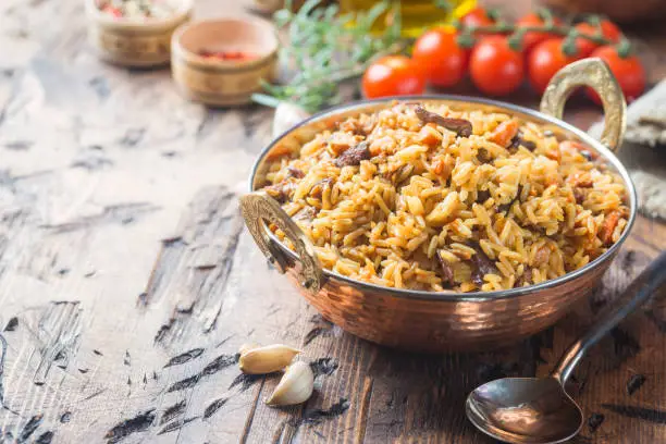 Lamb pilaf in a bowl on wooden rustic background with copy space