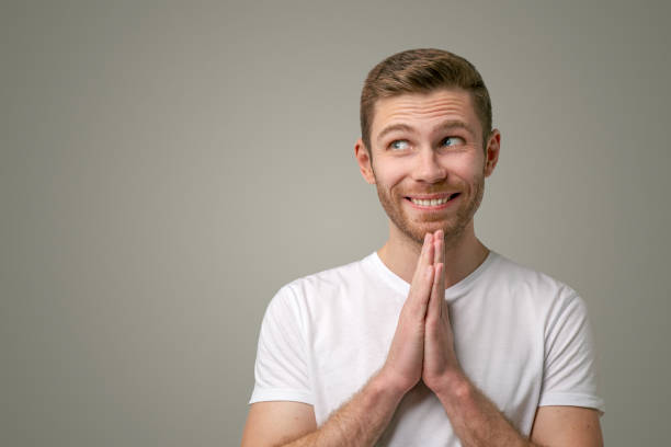 The bearded man holds hands together as if in prayer, begging for money, looking to the left with great desire. The boyfriend asks for a favor, makes a gesture of request, stands on white background The bearded man holds hands together as if in prayer, begging for money, looking to the left with great desire. The boyfriend asks for a favor, makes a gesture of request, stands on white background. doing a favor stock pictures, royalty-free photos & images