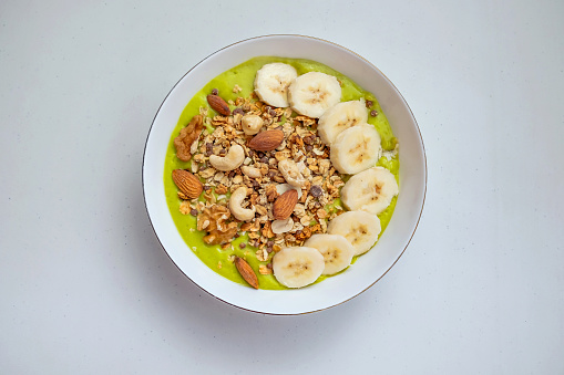 Close up avocado smoothie bowl, with banana , granola and healthy nuts