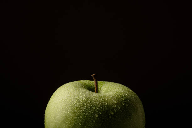 istock Green apple with water drops on a black background. 1070400438