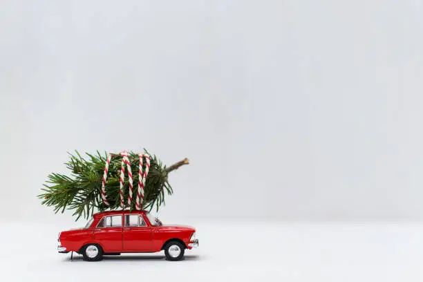 Photo of Red toy car with a christmas tree on the roof