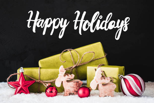 English Calligraphy Happy Holidays. Green Christmas Decoration Like Balls Gifts And Reindeer. Black Cement Background With Snow