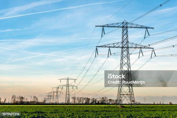 Torres De Alta Tensión Con Gruesas Colgando De Cables De Potencia En Un Paisaje Rural En Los Países Bajos Foto de stock y más banco de imágenes de Cable de conducción eléctrica