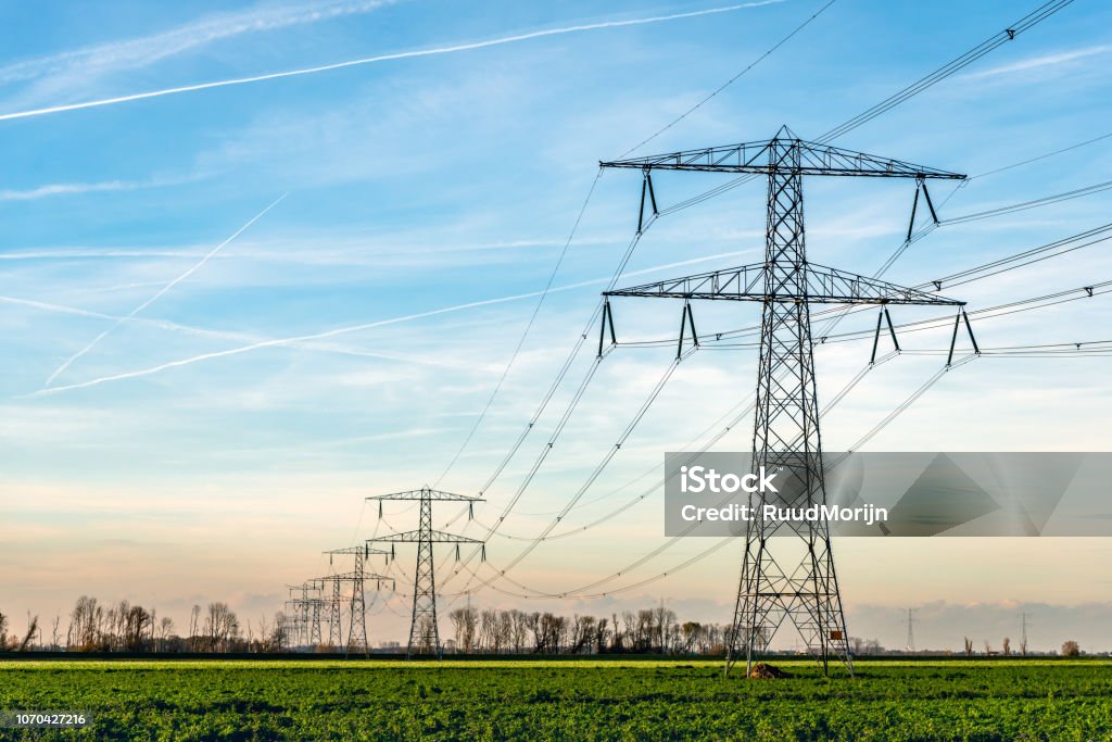 High voltage towers with thick hanging power cables in a rural landscape in the Netherlands Overview of power pylons and high voltage lines in a long row in a rural landscape. The photo was taken in De Biesbosch, a nature area near the village of Werkendam,  North Brabant, Netherlands Power Line Stock Photo
