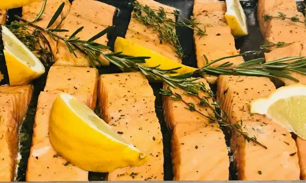 Close up grilled salmonslice with lemon rosemary thyme on warm tray ,fish backgrounds,