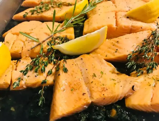 close up grilled salmon slice with lemon ,rosemary ,thyme und spinach ,fish backgrounds,