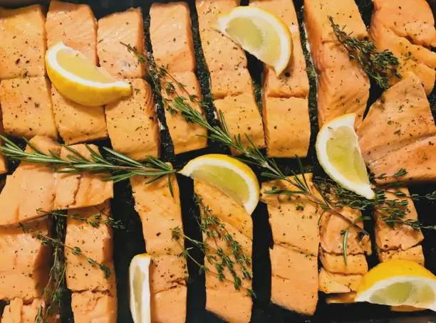 Top view grilled salmonslice with lemon rosemary thyme onwarm tray,fish backgrounds,