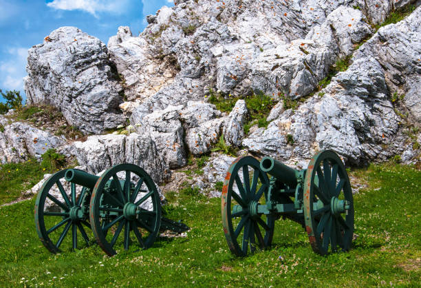 istock guns standing next to a large stone on a green hill 1070472968