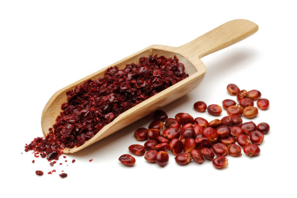 Sumac berries and ground sumac in a wooden scoop Sumac berries and ground sumac in a wooden scoop isolated on white background sumac stock pictures, royalty-free photos & images