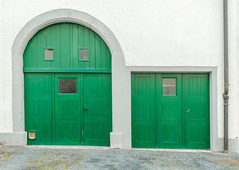detailed view of a house front with white plaster stone walls and bright green doors in the picturesque village of Neunkirch in Switzerland