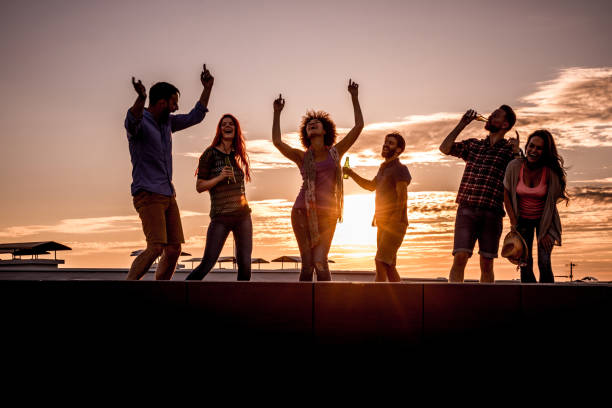 istock Large group of young happy people having fun while dancing on a rooftop at sunset. 1070478952
