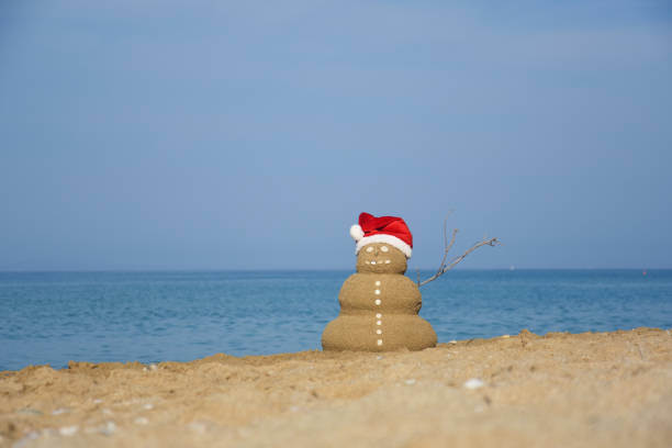 istock Sandy Christmas snowman with Santa hat at sunny beach 1070480292
