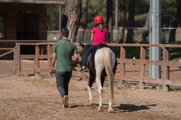 a nervous young girl taking a riding lesson - teaching child horseback riding horse imagens e fotografias de stock