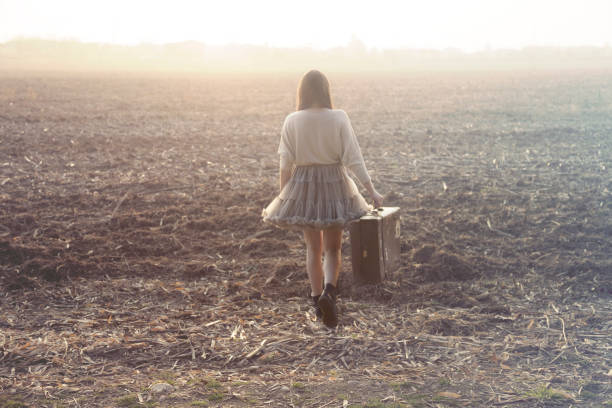 Woman with suitcase walking toward infinity in a desert place