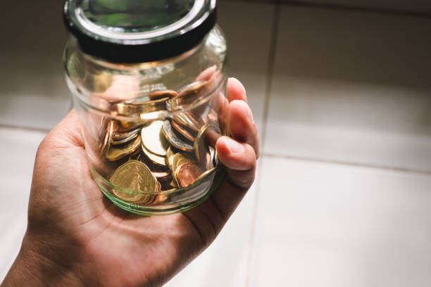 istock Closeup hand holding coins in glass jar 1070492196