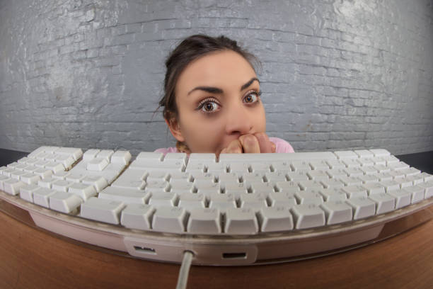 business woman sticking out from behind the keyboard - employee theft imagens e fotografias de stock