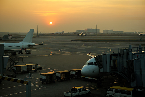 Planes on airport tarmac in dramatic sunset light.