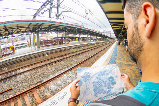 A young male backpacker tourist missed looking to a map while is waiting for a train / metro at the main railway station in Sydney, New South Wales, Australia
