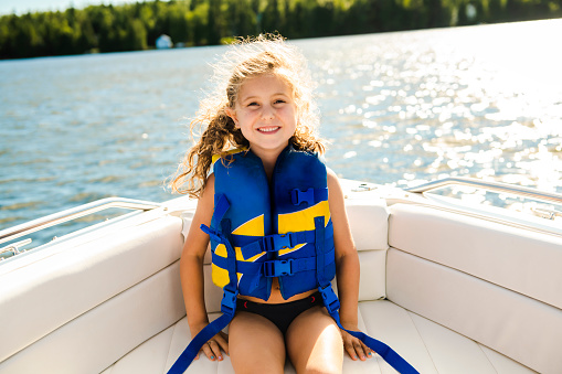 A child with safety vest on the lake boat