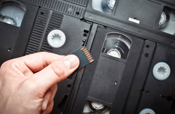 Hand holding mini sd card on video cassette background