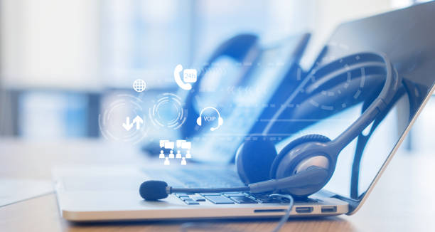 close up headset of call center and laptop with virtual futuristic communication telephony VOIP technology on office desk in monitoring room for network operation job concept close up headset of call center and laptop with virtual futuristic communication telephony VOIP technology on office desk in monitoring room for network operation job concept voip stock pictures, royalty-free photos & images