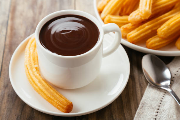 Delicious chocolate with churros Traditional spanish churros with hot chocolate sauce on a rustic wooden table spanish breakfast stock pictures, royalty-free photos & images