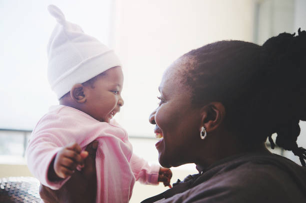 African grandmother and baby granddaughter intimate time side view An African grandmother holding a baby daughter intimately close indoors Strand Cape Town South Africa nanny photos stock pictures, royalty-free photos & images