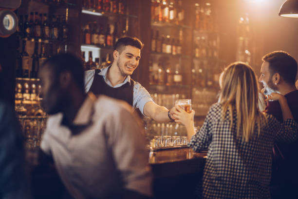 istock Young happy bartender serving beer to his customers in a bar. 1070519224