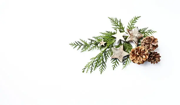 Photo of An arrangement of evergreen twigs, cones and Christmas decorations. Flatlay. Copy space. White background