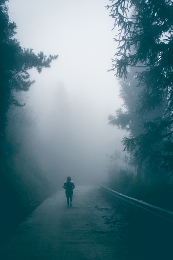 Young woman walking on foggy road lonely