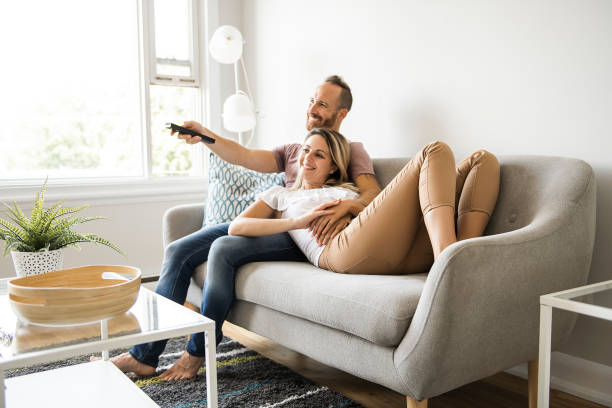 自宅テレビでカップルが自宅のリビング ルームで快適なソファに座っています。 - apartment television family couple ストックフォトと画像