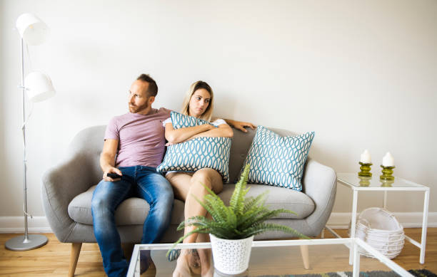 разрыв пара сидит в удобном диване в гостиной дома - family television fighting watching стоковые фото и изображения