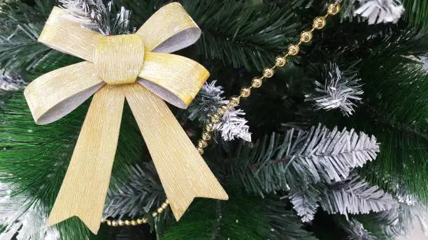 Christmas decoration in the form of a Golden bow hanging on the Christmas tree