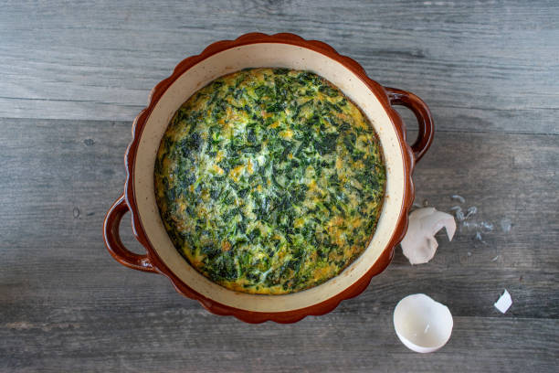 spinach souffle in rustic round dish with egg shells stock photo