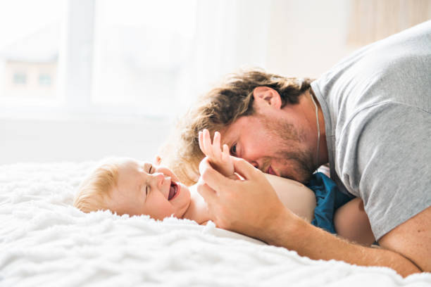 père et bébé fille sur un lit - tickling photos et images de collection