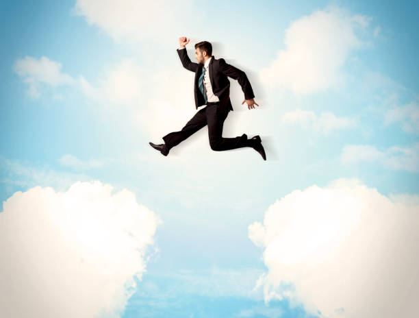 istock Business person jumping over clouds in the sky 1070560914