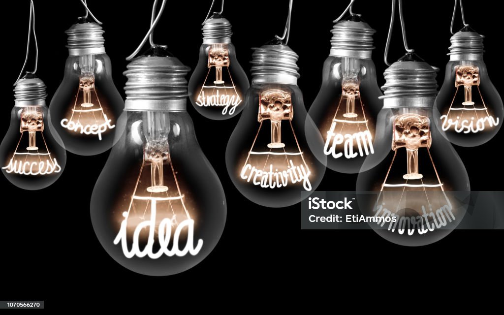 Light Bulbs Concept Photo of light bulbs with shining fibers in a shape of IDEA concept related words isolated on black background Innovation Stock Photo