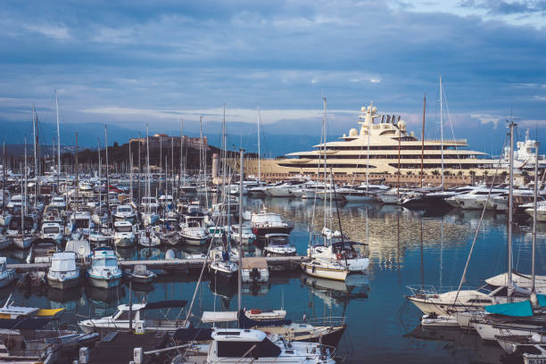 Cannes, France - October 10, 2018. City of Cannes harbour, one of the most popular cities in French riviera. It is full of stylish people and tourists from all over the world. Many luxury yachts, and one in the background - a largest private yacht in the world - Dilbar. It is 156 m (512 ft) long.