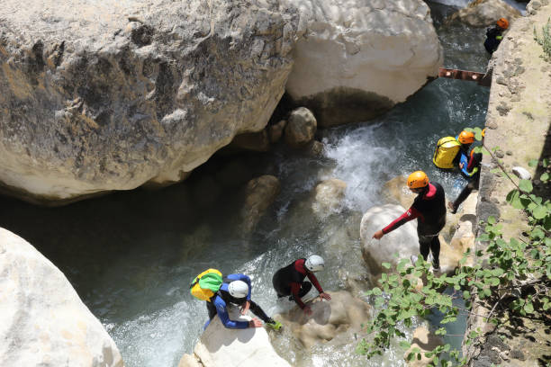 People practicing canyoning in the Vero river canyon, with helmets, protections and diving suits among the rocks during summer in Alquezar, Spain Alquezar, Spain - August 25, 2018: People practicing canyoning in the Vero river canyon, with helmets, protections and diving suits among the rocks during summer in Alquezar, Spain canyoneering stock pictures, royalty-free photos & images