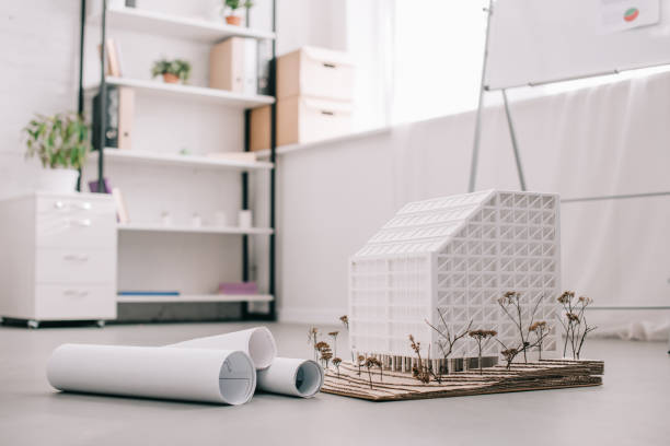 istock modern architect office design with blueprints and house model on foreground 1070582080