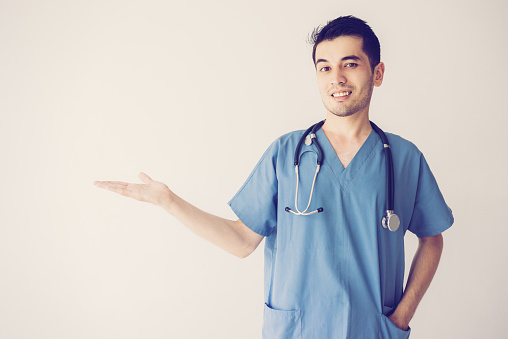 Smiling male doctor holding empty space on palm and presenting product. Medical product advertising concept. Isolated front view on white background.