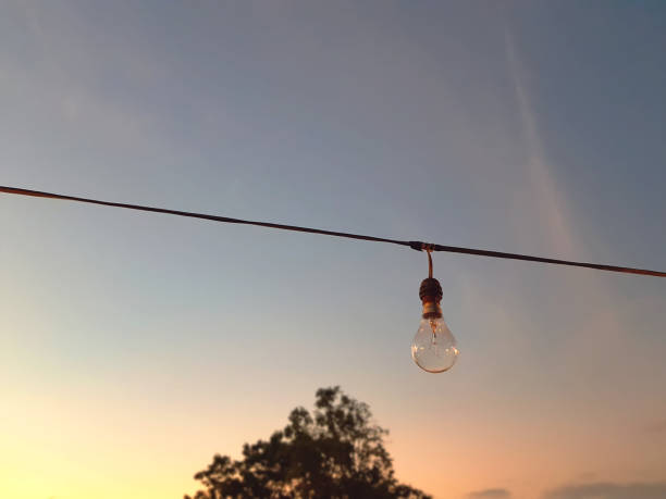 istock Low Angle View of Hanging Incandescent Lamp Against Sky During Sunset 1070591340