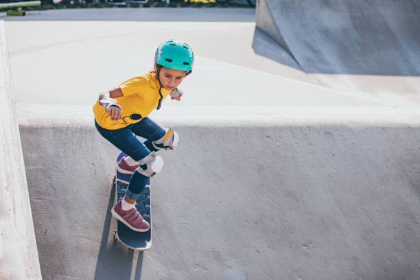 Young Skateboarding Girl Dropping From a Bank in Skatepark Young Skateboarding Girl Dropping From a Bank in Skatepark. skateboarding stock pictures, royalty-free photos & images
