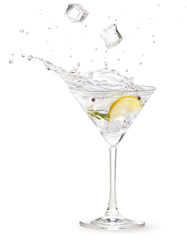 ice cubes falling into a gin martini cocktail splashing on white background